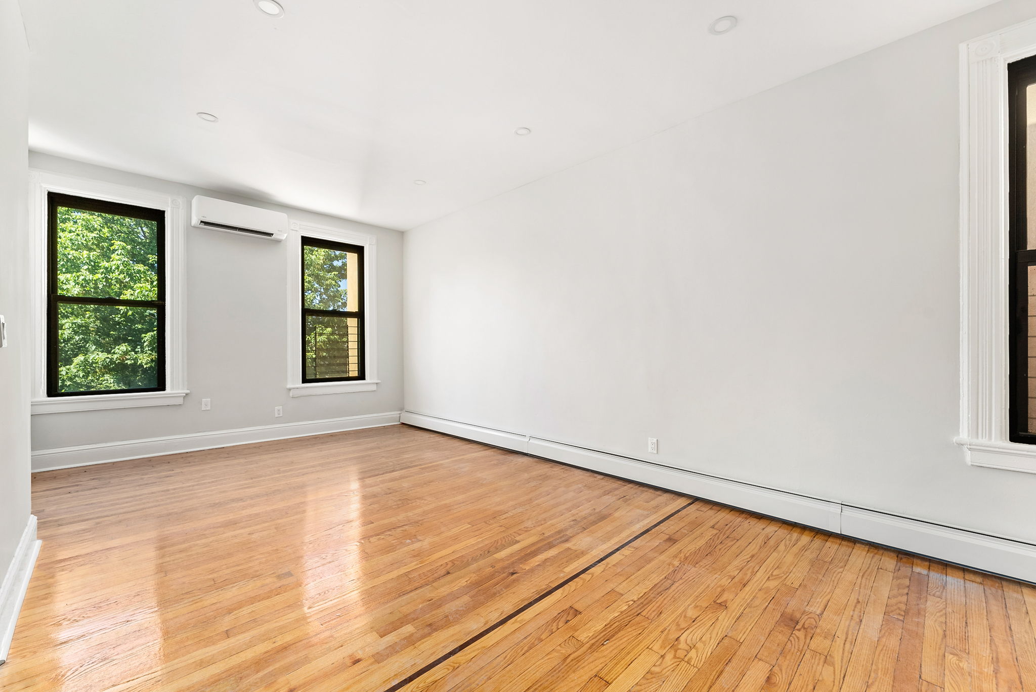 1414 30th Road Queens, NY 11102 - Photo 6 of 16 an empty room with wooden floor and windows