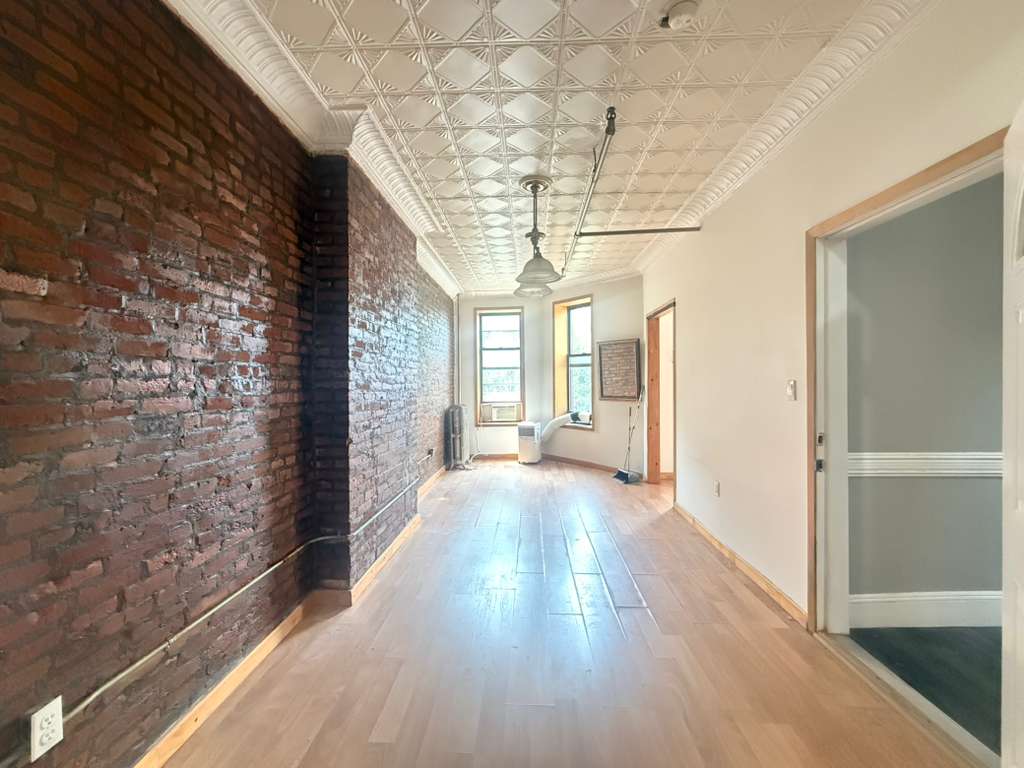 313 Van Buren Street Brooklyn, NY 11221 - Photo 4 of 20 a view of a hallway with wooden floor and chandelier