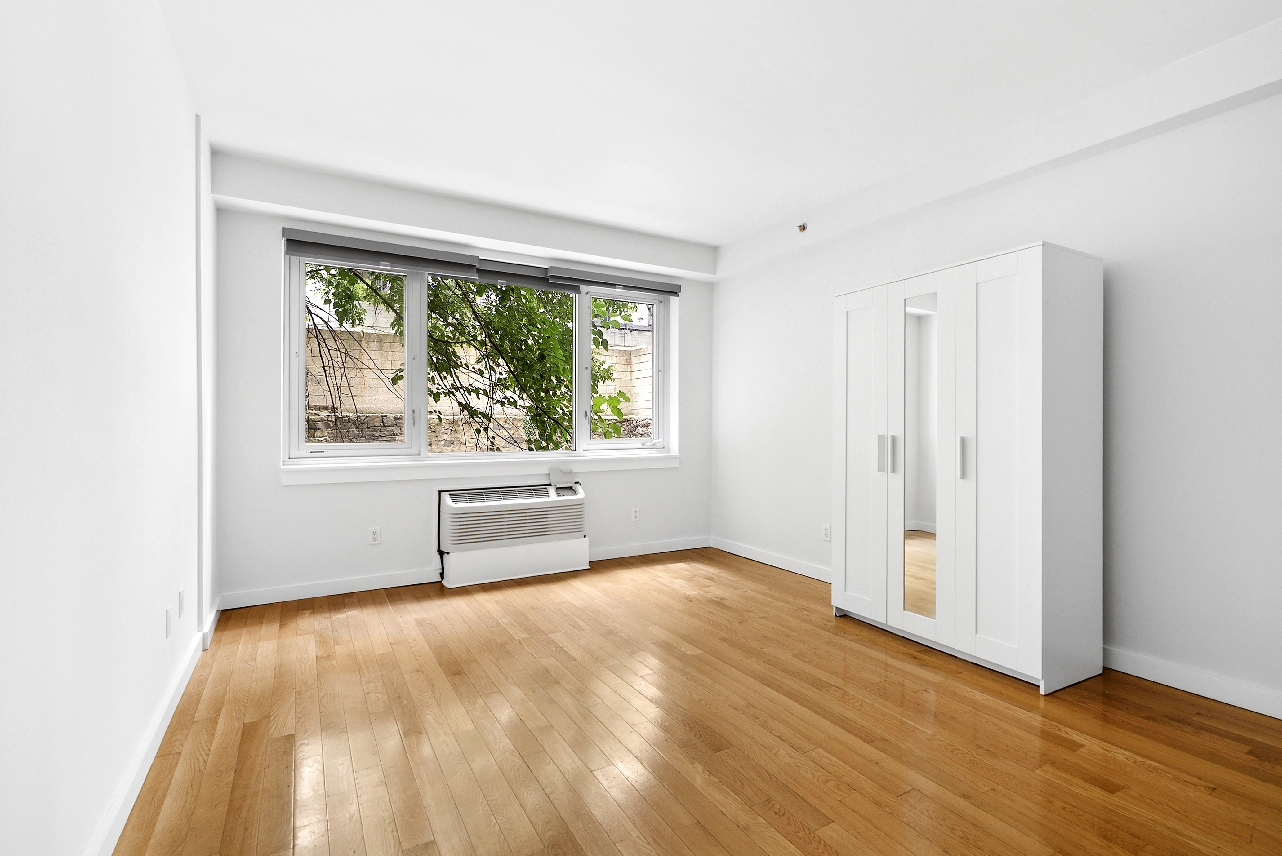 450 East 117th Street, Unit 1A Manhattan, NY 10035 - Photo 6 of 10 a view of an empty room with wooden floor and a window
