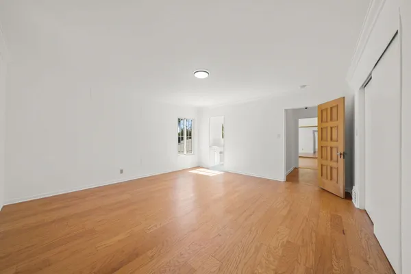 a view of empty room with wooden floor and fan