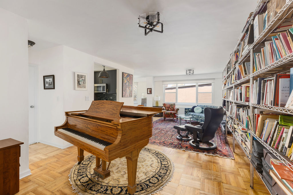 101 West 12th Street, Unit 5V Manhattan, NY 10011 - Photo 10 of 26 a living room with furniture a bookshelf and a window