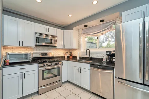 a kitchen with cabinets appliances a sink and a window