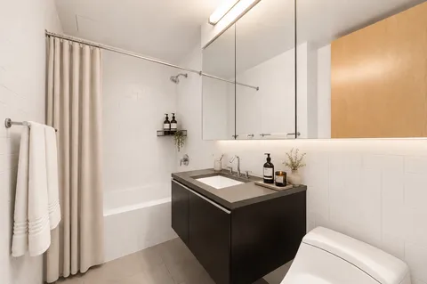a bathroom with a granite countertop sink a mirror and a bathtub