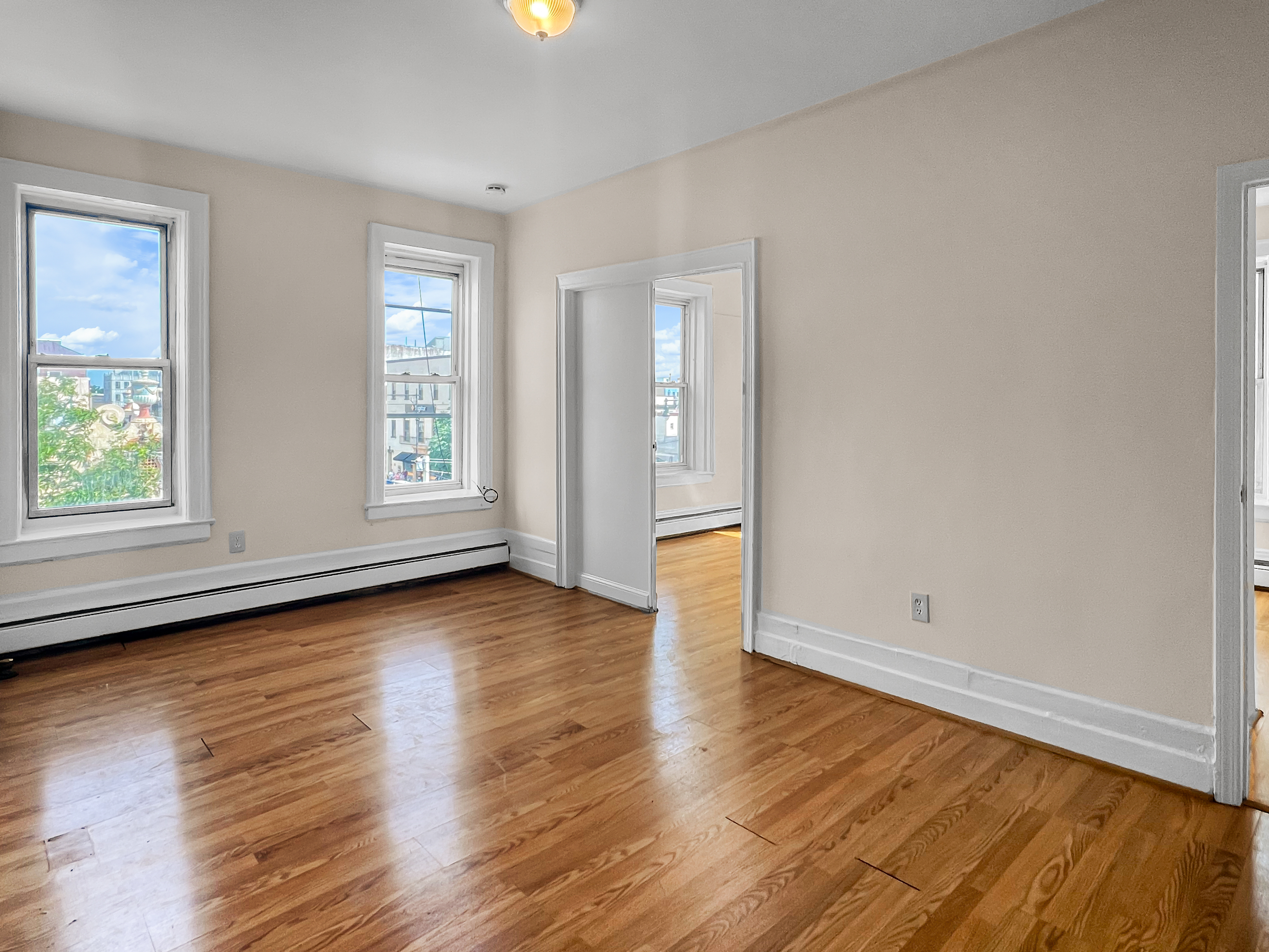 35-19 Broadway, Unit 3 Queens, NY 11106 - Photo 1 of 11 an empty room with wooden floor and windows