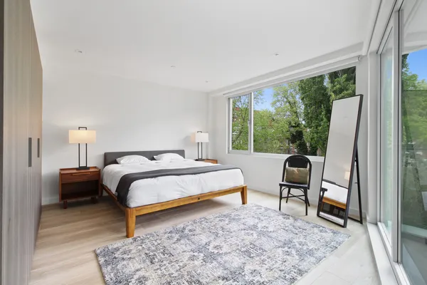 a bedroom with a bed a table and a dresser next to a window