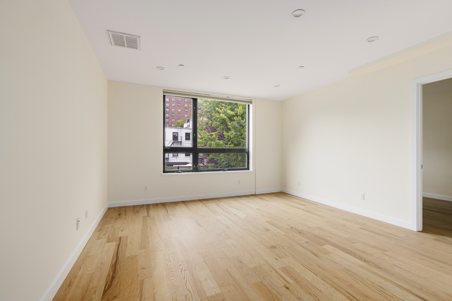 74 Adelphi Street, Unit 2B Brooklyn, NY 11205 - Photo 3 of 9 an empty room with wooden floor and windows
