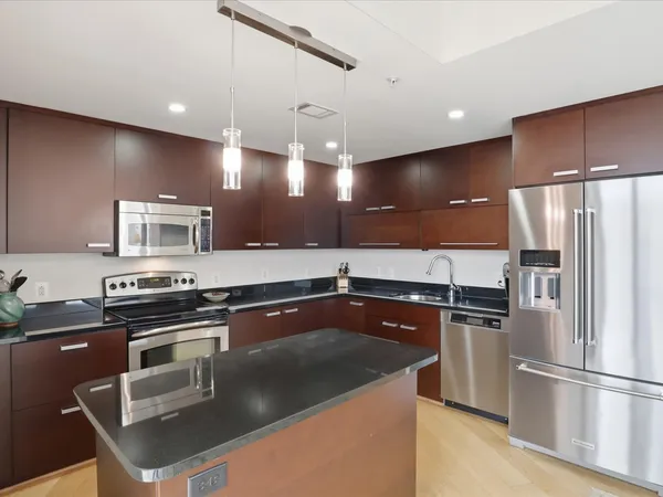 a kitchen with stainless steel appliances granite countertop a sink a stove and a refrigerator
