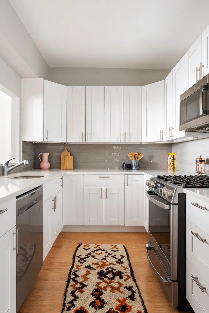 a kitchen with stainless steel appliances granite countertop a stove and white cabinets