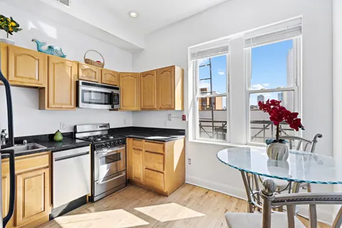 a kitchen with stainless steel appliances granite countertop a stove top oven a sink dishwasher and white cabinets with wooden floor