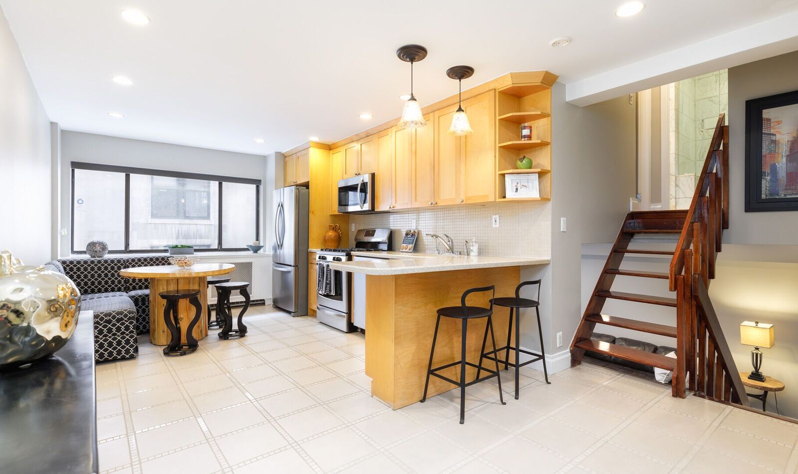 7 East 35th Street, Unit 10D Manhattan, NY 10016 - Photo 1 of 8 a kitchen with stainless steel appliances kitchen island granite countertop dining table chairs and a refrigerator