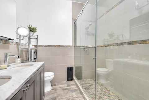 a bathroom with a granite countertop sink a toilet and shower