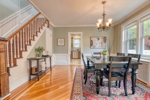 a view of a dining room and livingroom with furniture wooden floor a chandelier and a painting