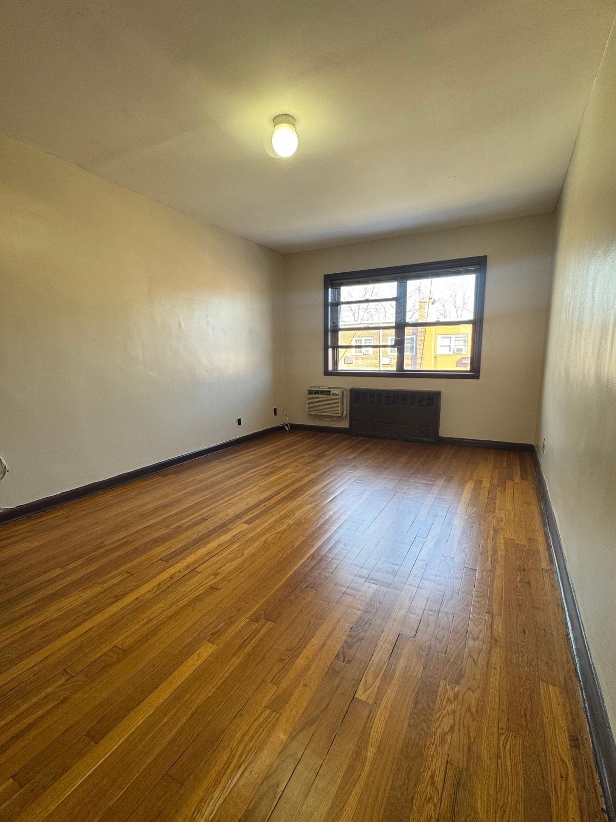 647 East 82nd Street, Unit 2 Brooklyn, NY 11236 - Photo 5 of 6 an empty room with wooden floor and windows