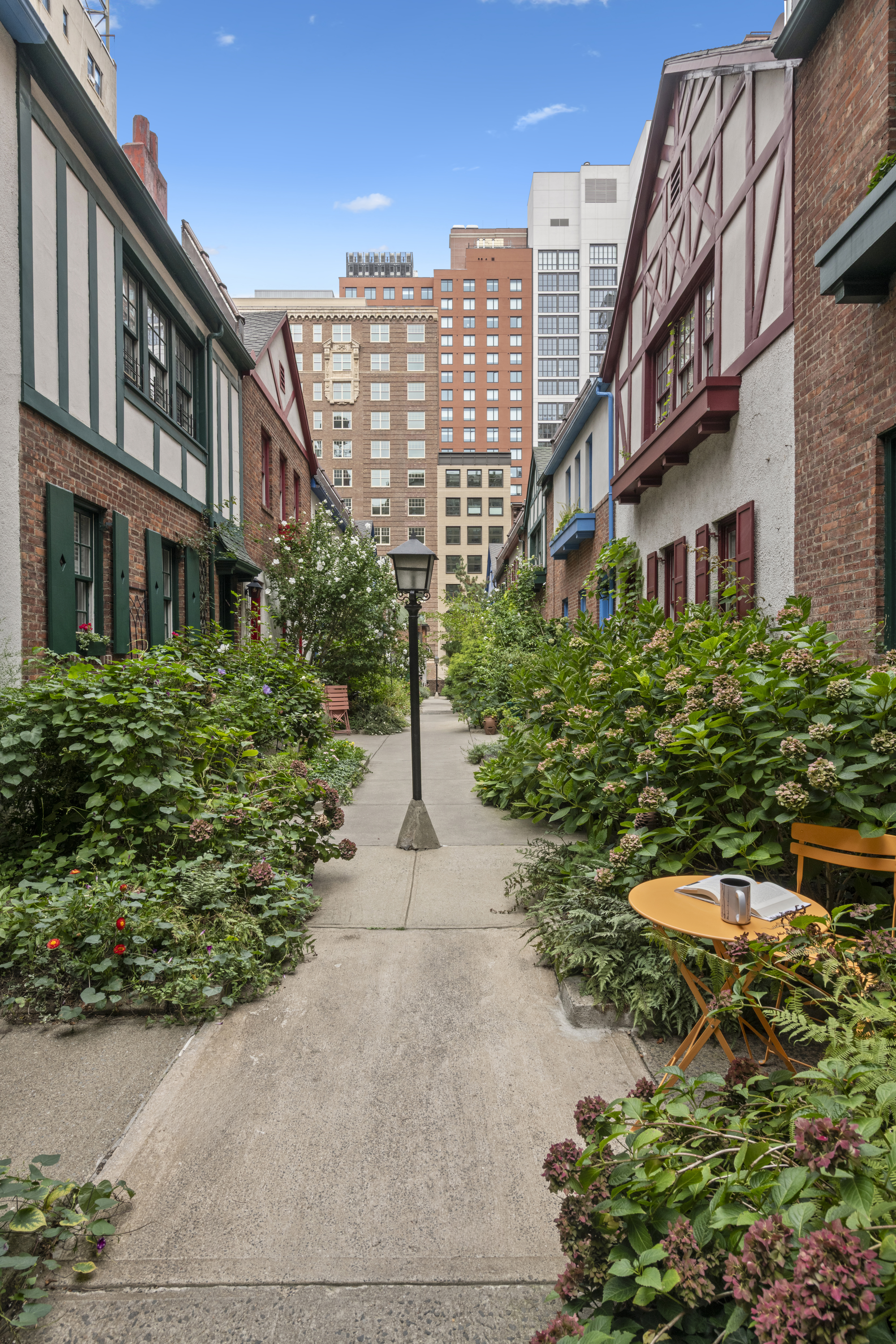 10 Pomander Walk, Unit 1 Manhattan, NY 10025 - Photo 9 of 13 a front view of a multi story residential apartment building with yard and outdoor seating