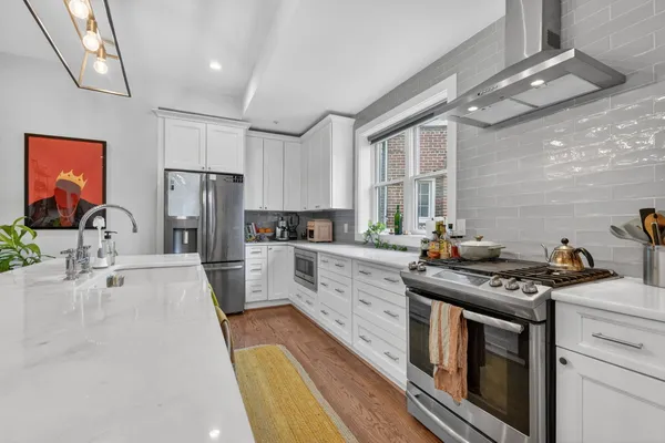a large kitchen with stainless steel appliances granite countertop a lot of counter space and wooden floors
