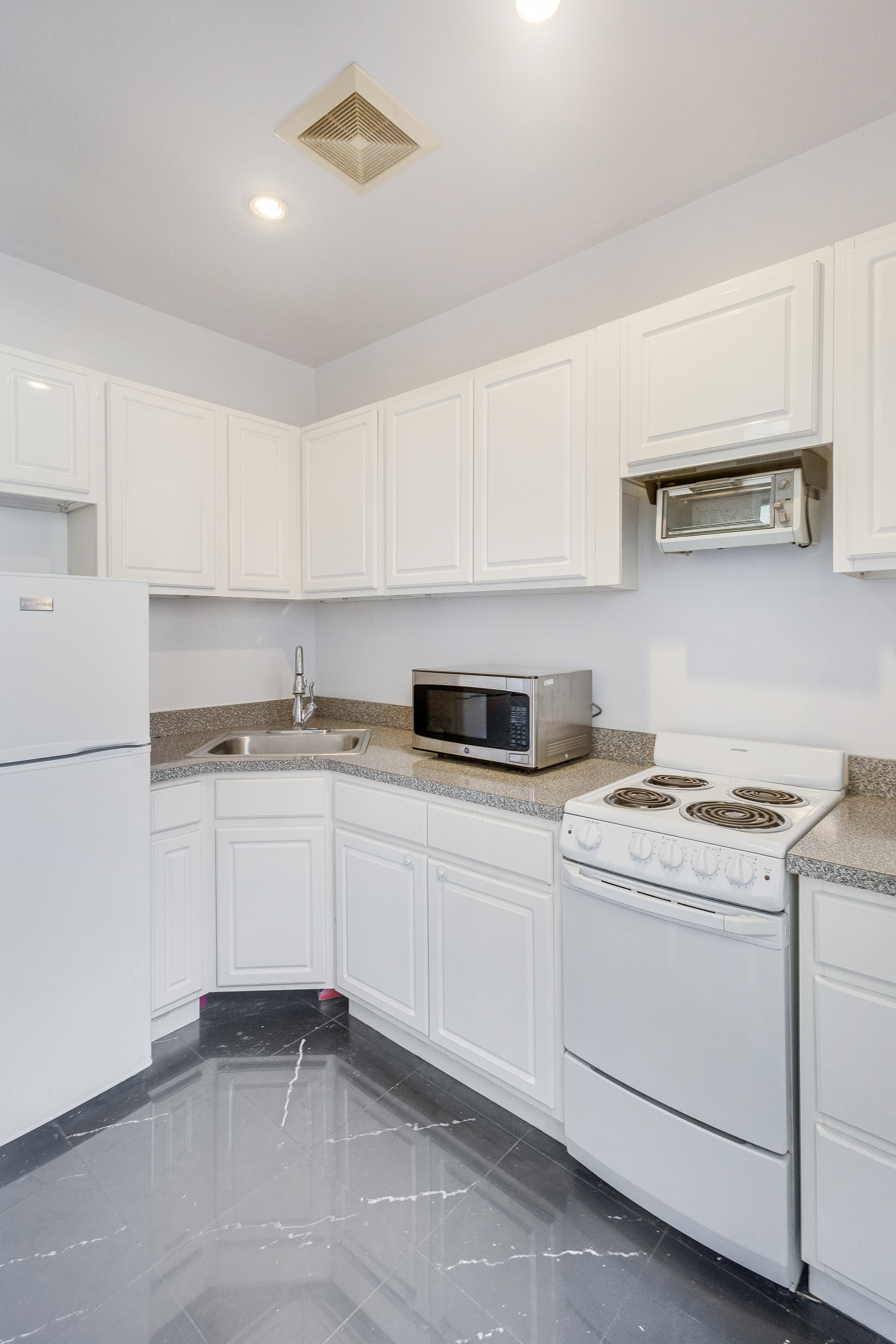 167 West 72nd Street Manhattan, NY 10023 - Photo 9 of 25 a kitchen with white cabinets stainless steel appliances and sink