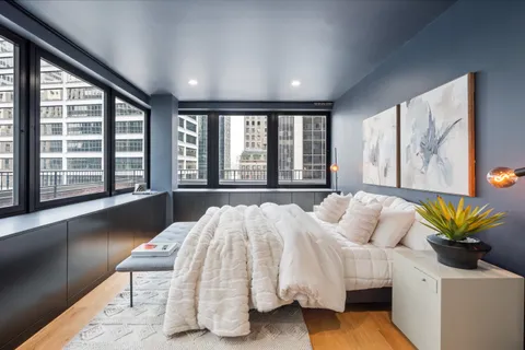 a bed sitting in a spacious bedroom next to a large window