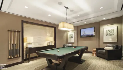a room with furniture pool table wooden floor and windows