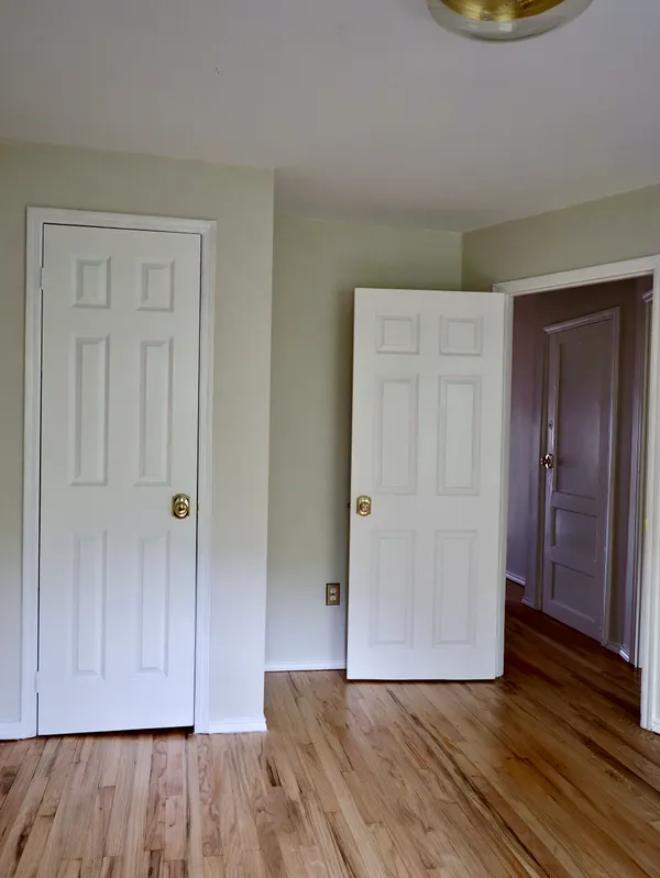 a view of an empty room with wooden floor and closet