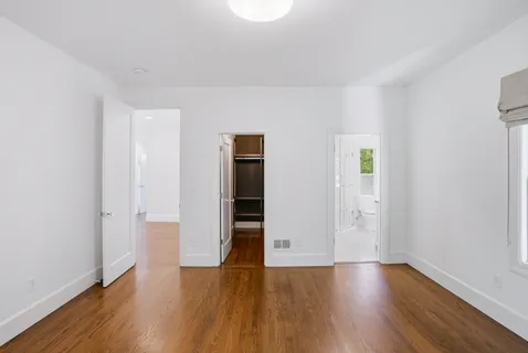 an empty room with wooden floor & closet and windows