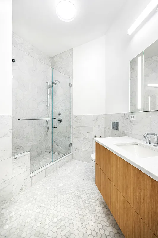 395 Broadway, Unit 5B Manhattan, NY 10013 - Photo 5 of 13 a bathroom with a granite countertop sink a mirror and shower