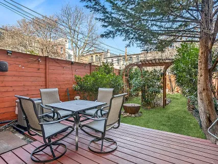 a view of a patio with table and chairs with wooden floor and fence