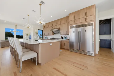 a kitchen with stainless steel appliances kitchen island granite countertop a refrigerator a sink and a stove