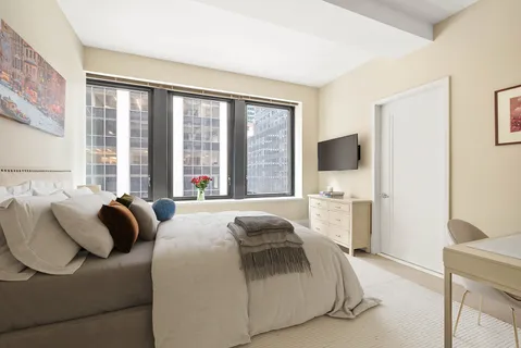 a bedroom with a bed and a flat tv screen next to a window