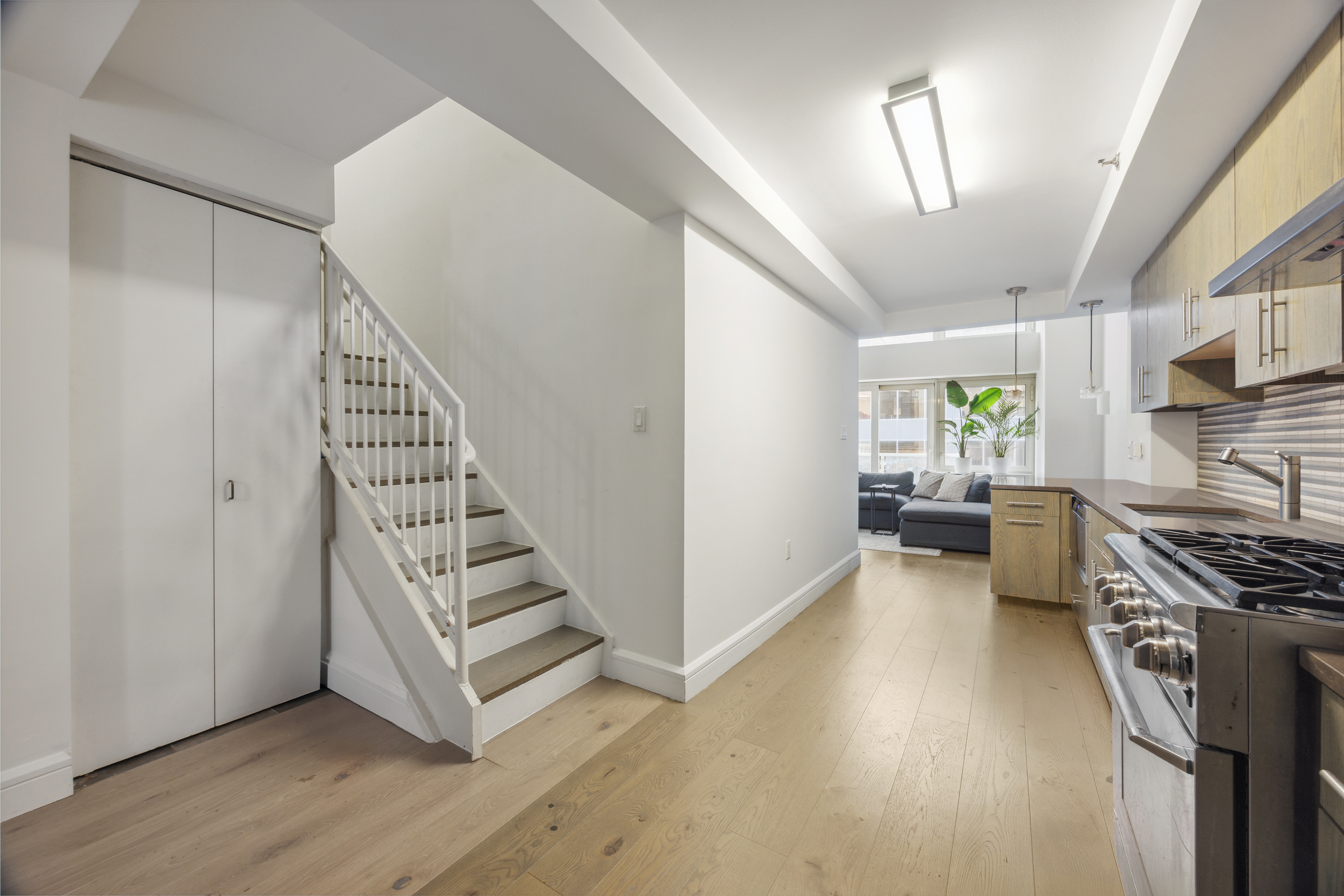 67 Liberty Street, Unit 10 Manhattan, NY 10005 - Photo 4 of 10 a view of a kitchen with wooden floor electronic appliances and stairs