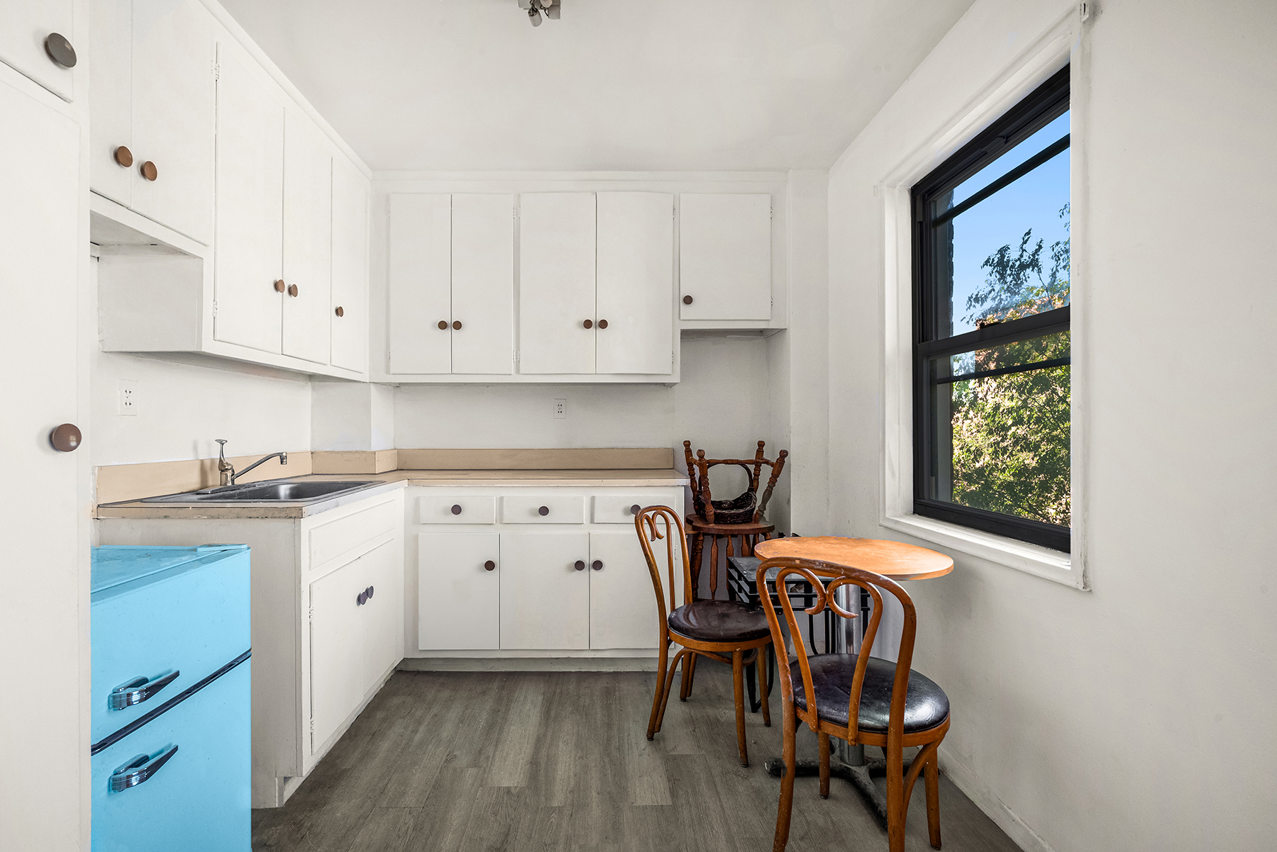 3131 Grand Concourse, Unit 7A Bronx, NY 10468 - Photo 3 of 5 a kitchen with stainless steel appliances a white table chairs and a refrigerator