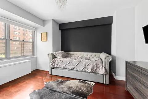 a bedroom with a bed window and wooden floor