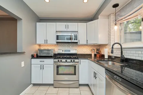 a kitchen with granite countertop a stove sink and microwave