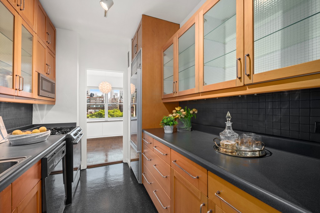 20 East 9th Street, Unit 12X Manhattan, NY 10003 - Photo 10 of 26 a kitchen with granite countertop stainless steel appliances a sink stove and cabinets