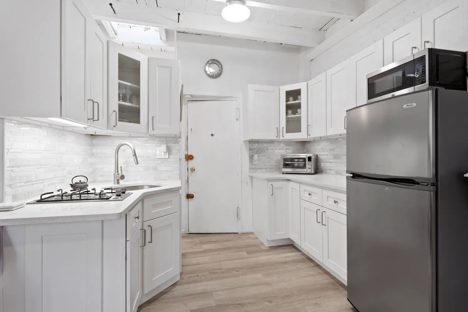 a kitchen with stainless steel appliances granite countertop a refrigerator sink stove and white cabinets