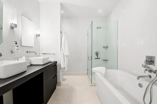 a bathroom with a tub sink double vanity and mirror