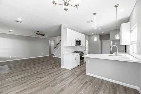 a kitchen with stainless steel appliances a sink a stove a refrigerator and island with wooden floor