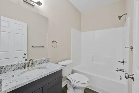 a bathroom with a granite countertop sink a toilet and shower