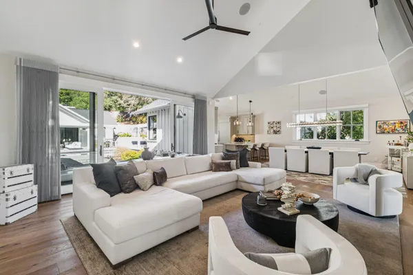 a kitchen with stainless steel appliances a sink a stove a refrigerator cabinets and living room view