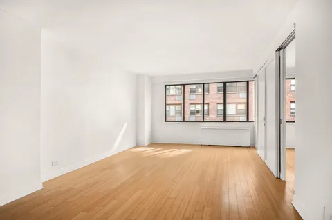 a view of an empty room with a window and wooden floor