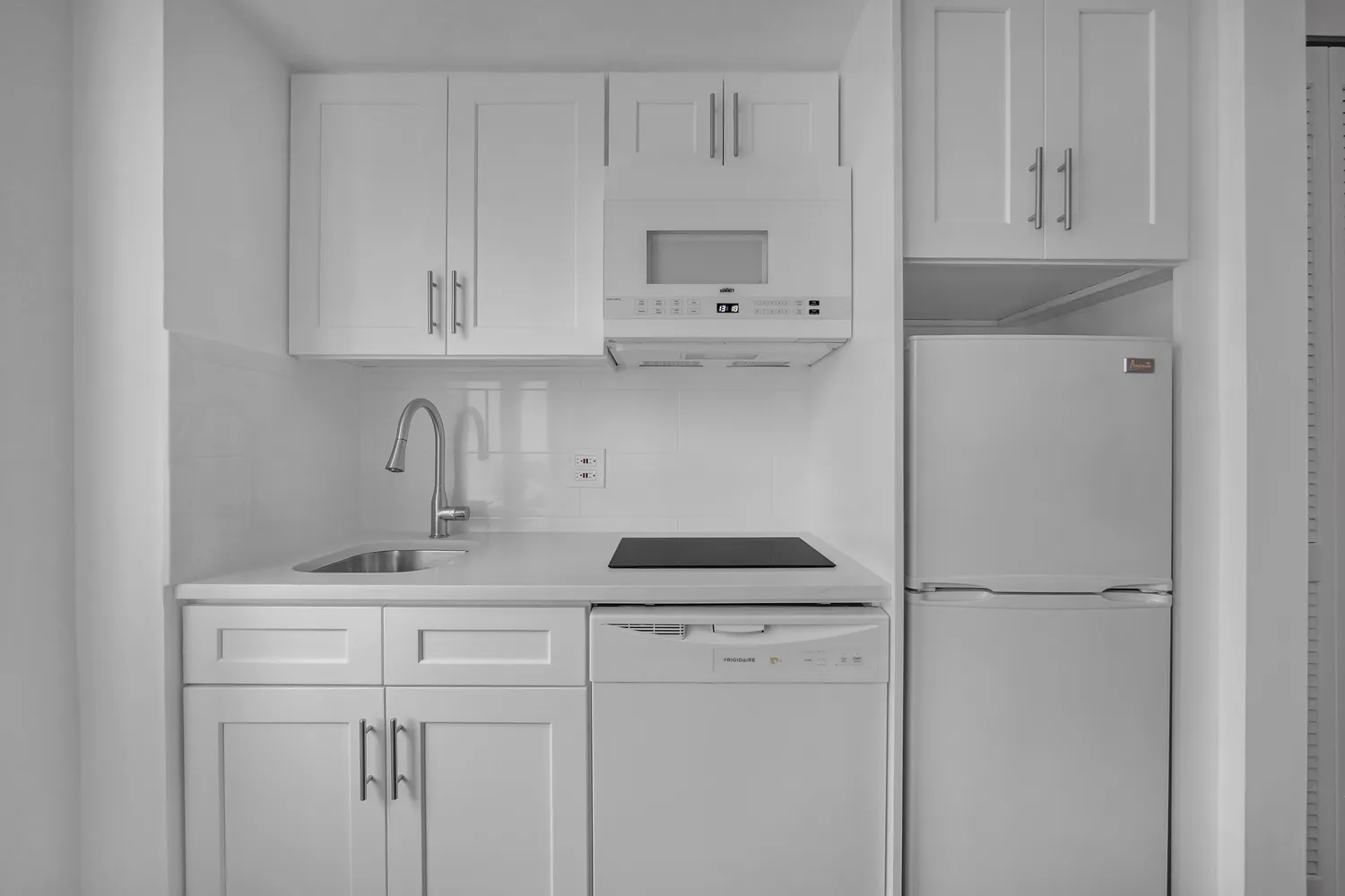 a kitchen with white cabinets and refrigerator