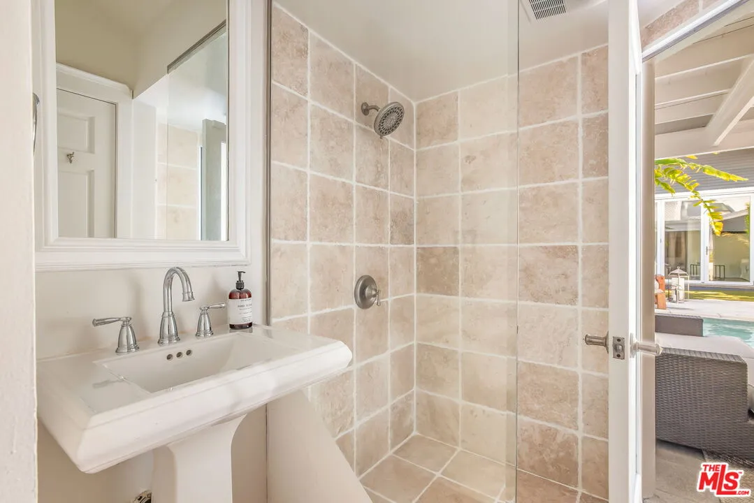 a bathroom with a sink shower and a mirror