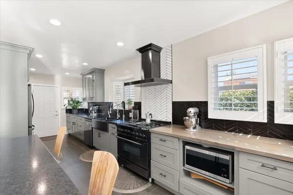 a room with stainless steel appliances kitchen island granite countertop a stove a sink a dining table and chairs with wooden floor