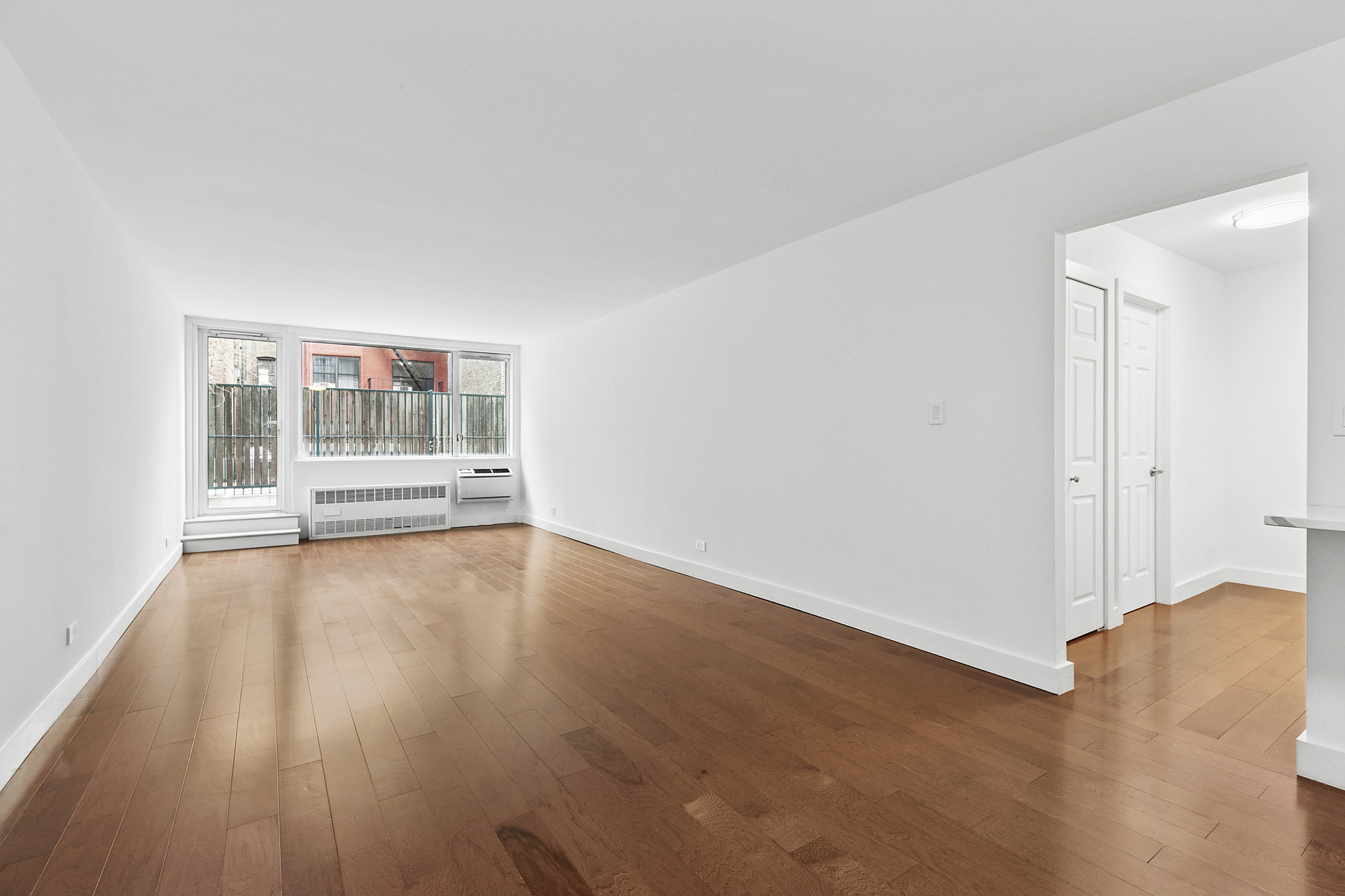 333 East 14th Street, Unit 2C Manhattan, NY 10003 - Photo 3 of 12 a view of an empty room with wooden floor and a window
