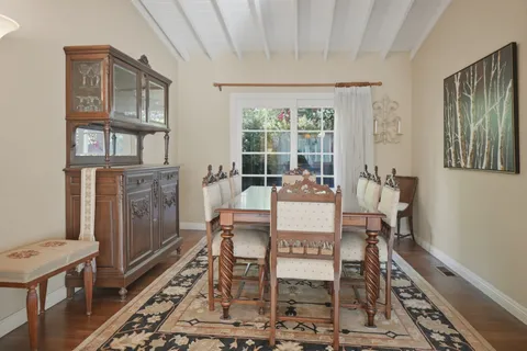 a kitchen with stainless steel appliances a stove a sink refrigerator and a dining table with wooden floor