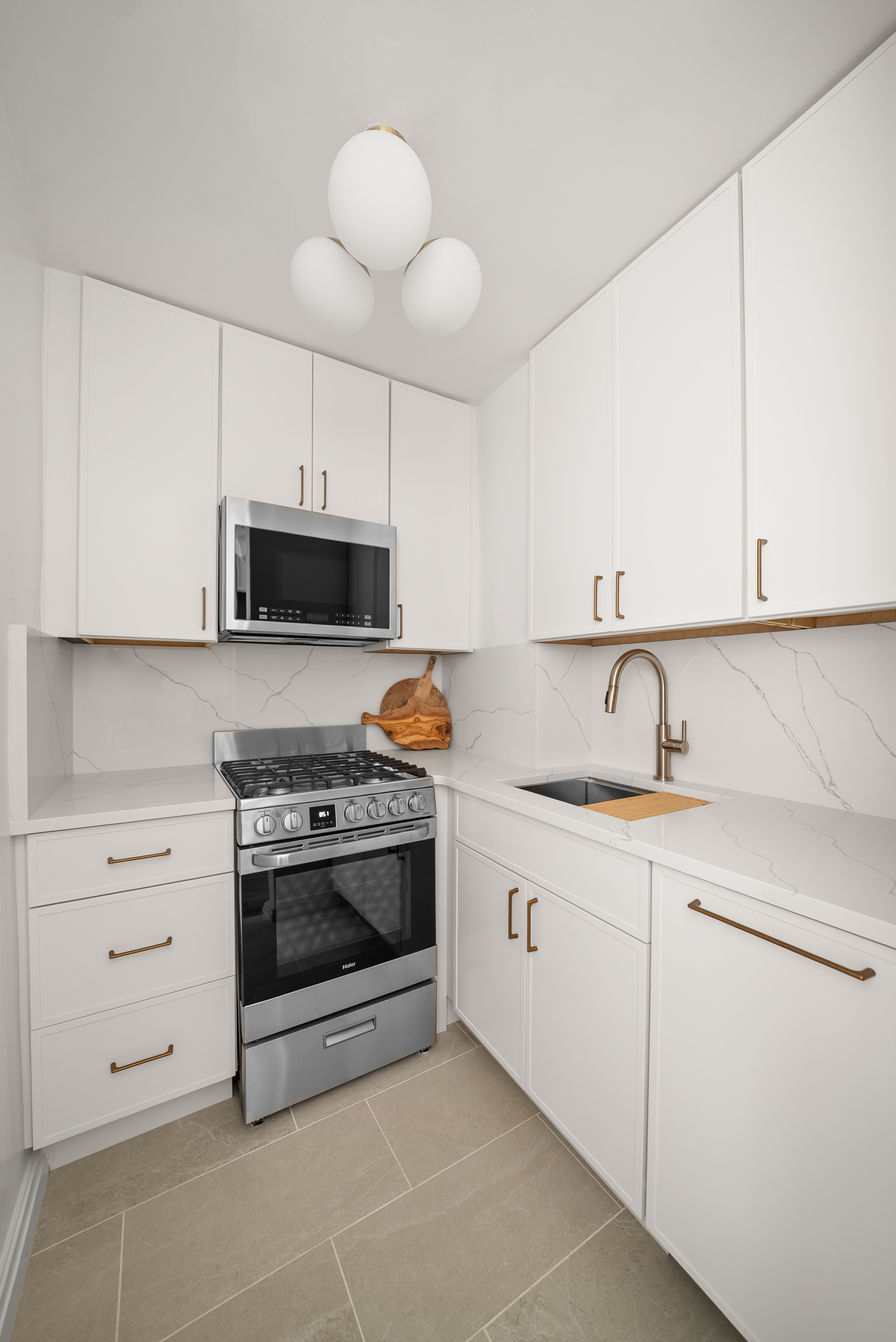 165 Christopher Street, Unit 6DD Manhattan, NY 10014 - Photo 5 of 8 a kitchen with granite countertop white cabinets and stainless steel appliances