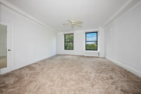 an empty room with windows and ceiling fan view