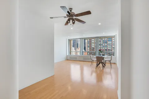 a view of a livingroom with wooden floor and a ceiling fan