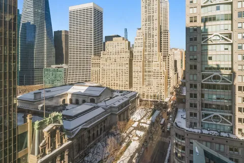 a view of a balcony with a couple of cars parked in front of buildings