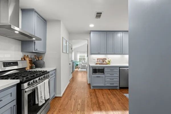 a kitchen with granite countertop a stove top oven a sink dishwasher and cabinets with wooden floor