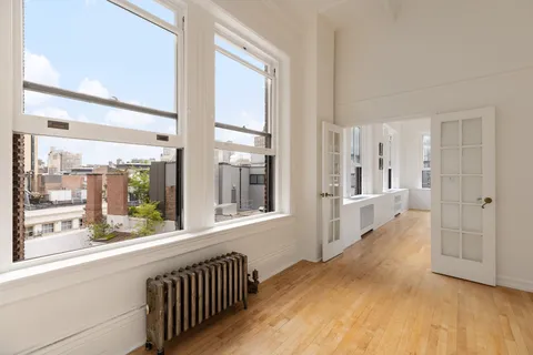 a view of a hallway with wooden floor and windows